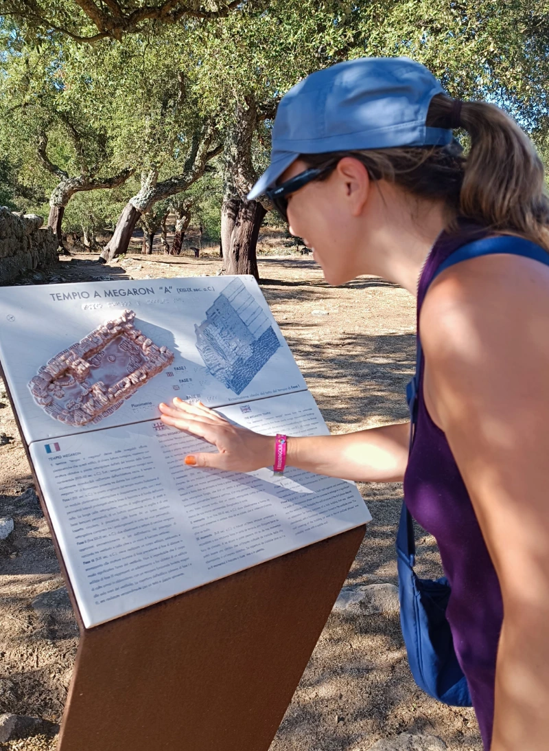 Silvia Maisonave explorando un panel exterior táctil en el área arqueológica de Romanzesu, Cerdeña